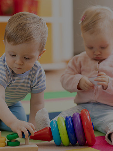 Two toddlers play together on floor.