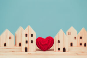 A crocheted heart nestled between tiny wooden houses.