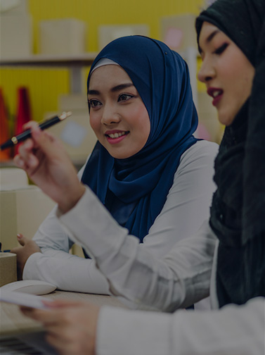 Two girls interacting with Zoom call on computer display.