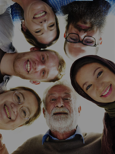 Multicultural group of people in huddle looking down at camera.