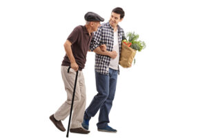 Young man carrying groceries assists older man with cane.