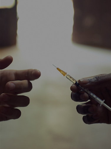 Closeup of a hand passing a loaded syringe to another hand.