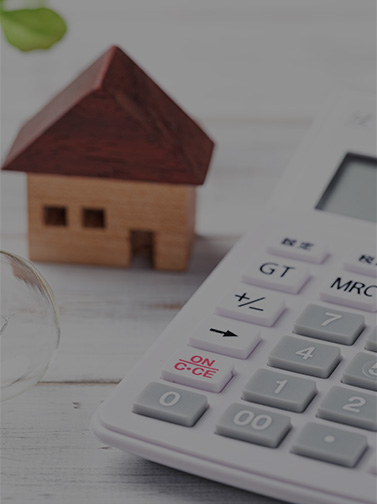 A tiny house sitting on a table next to a calculator.