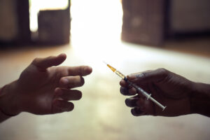 Closeup of a hand passing a loaded syringe to another hand.