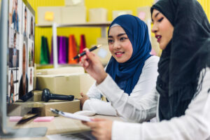 Two girls interacting with Zoom call on computer display.