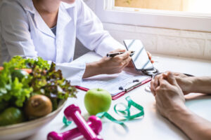 Two people sitting at table with fruit and vegetables.