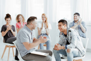 Adult program coordinator applauding with a group of teenagers.