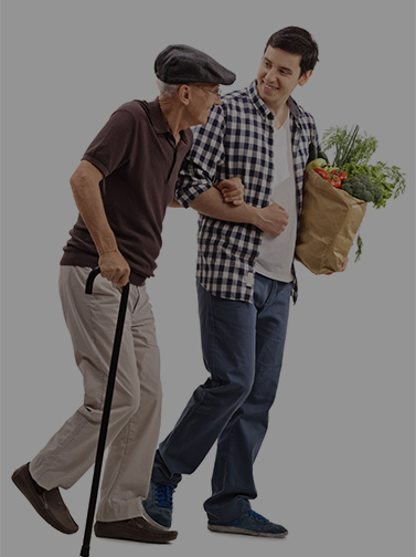 Young man carrying groceries assists older man with cane.