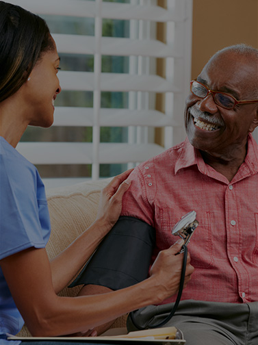 Medical professional tests blood pressure of elderly man.