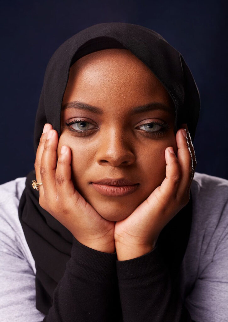 Girl wearing hijab resting her head on her hands.