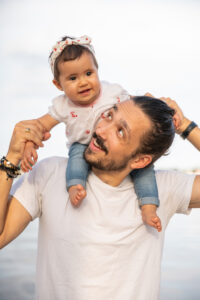 Man in white shirt with baby riding on shoulders.