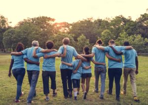 View from behind group of people walking together arm in arm.